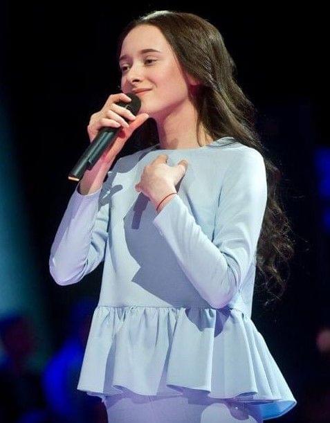 Photo of King's InterHigh student & singer, Eden, performing on stage wearing a blue outfit.