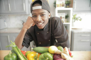 A picture of King's InterHigh student, Omari, behind a pile of vegetables.